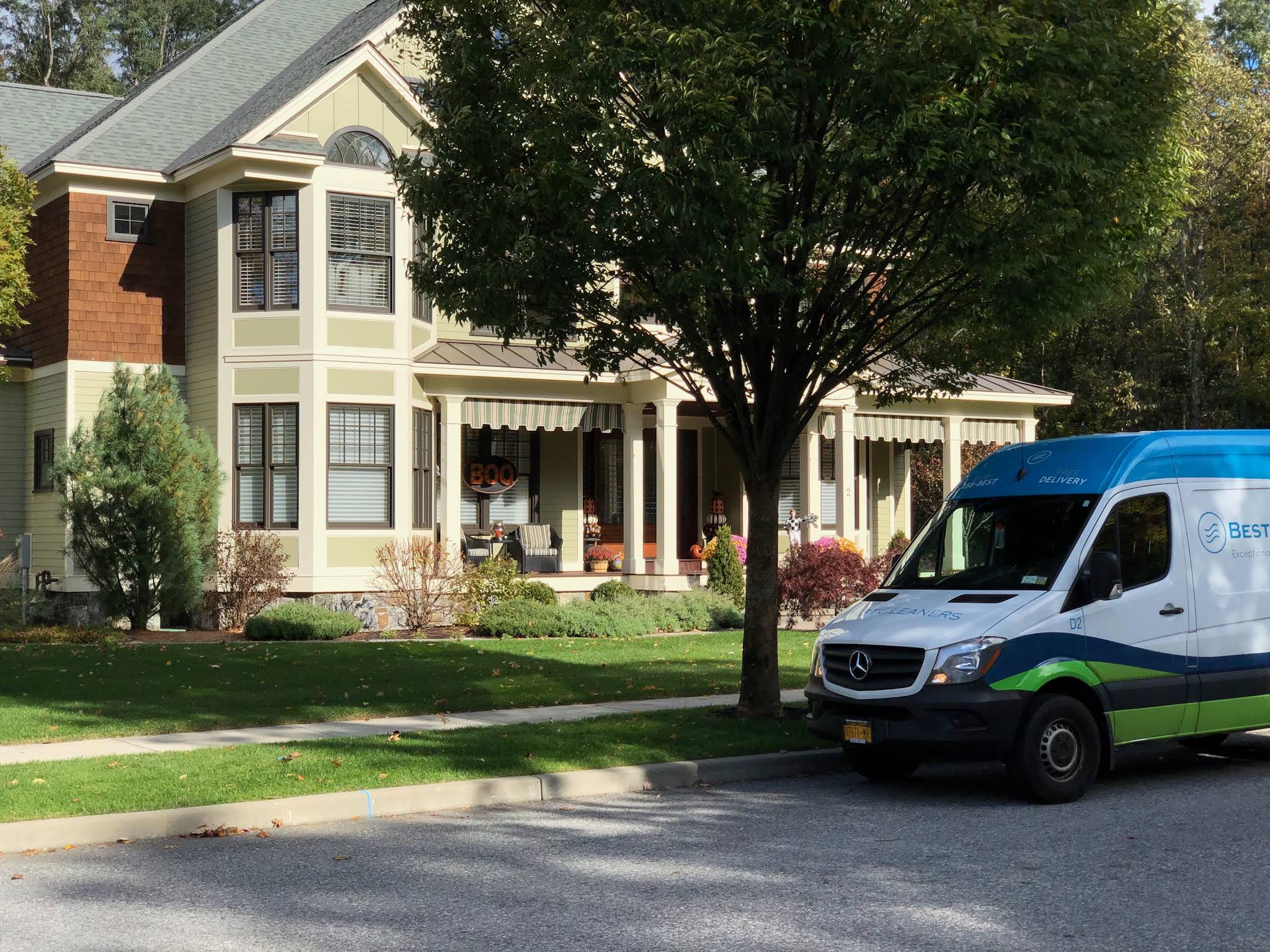A Best Cleaners pickup and delivery van parked in front of a neighborhood home.